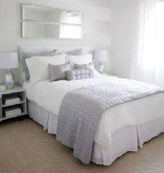 Beautiful bedroom features a gray wingback bed with silver nailhead trim dressed in soft white