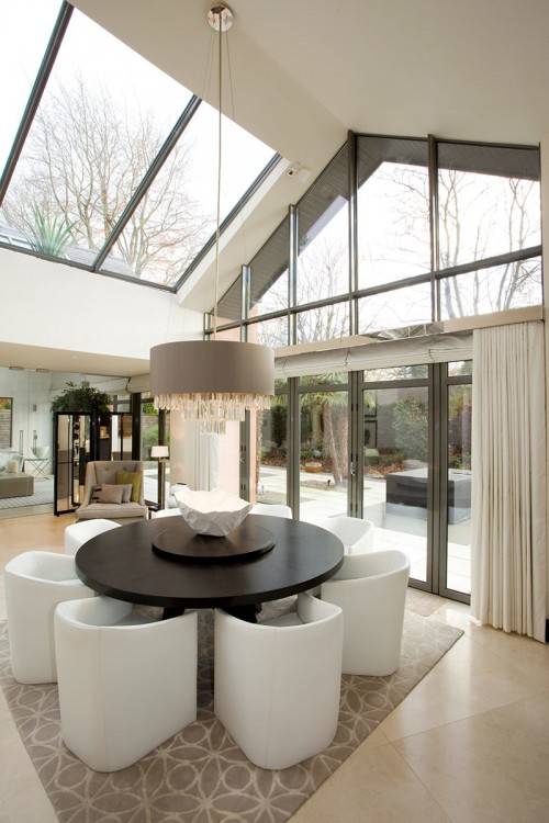 A classic conservatory in white uPVC with open doors displaying a dining  table inside