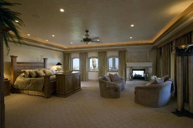 Another bedroom features large bed, gray walls and a seat on the corner