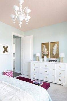 A pink ceiling beautifully complements light blue walls in this stylish  girl's bedroom decorated with white and gold feather art pieces mounted  above a