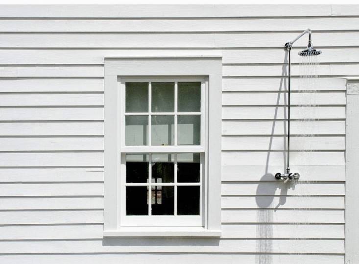 A pool house in the Berkshires in Massachusetts has an outdoor shower sided with white clapboard