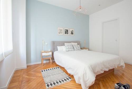 Scandinavian master bedroom with hardwood floor and bed with white covers